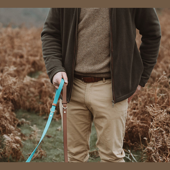 Front detail of a handler holding turquoise Biothane leads