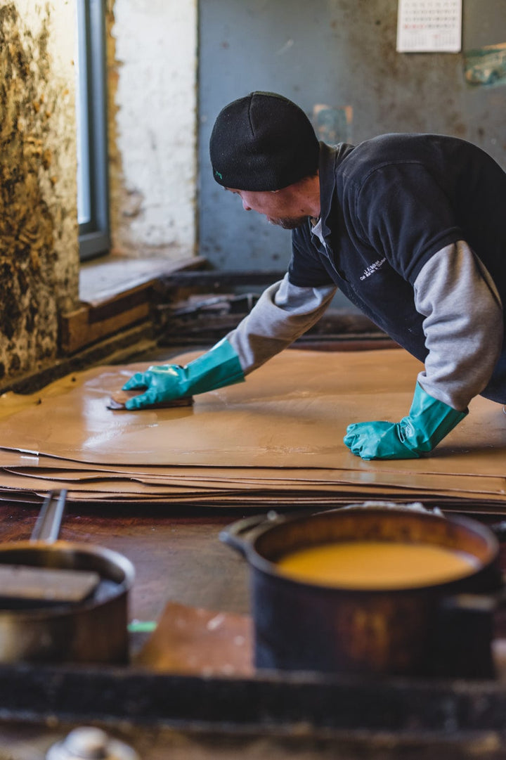 Tannery worker treating a leather hide by hand